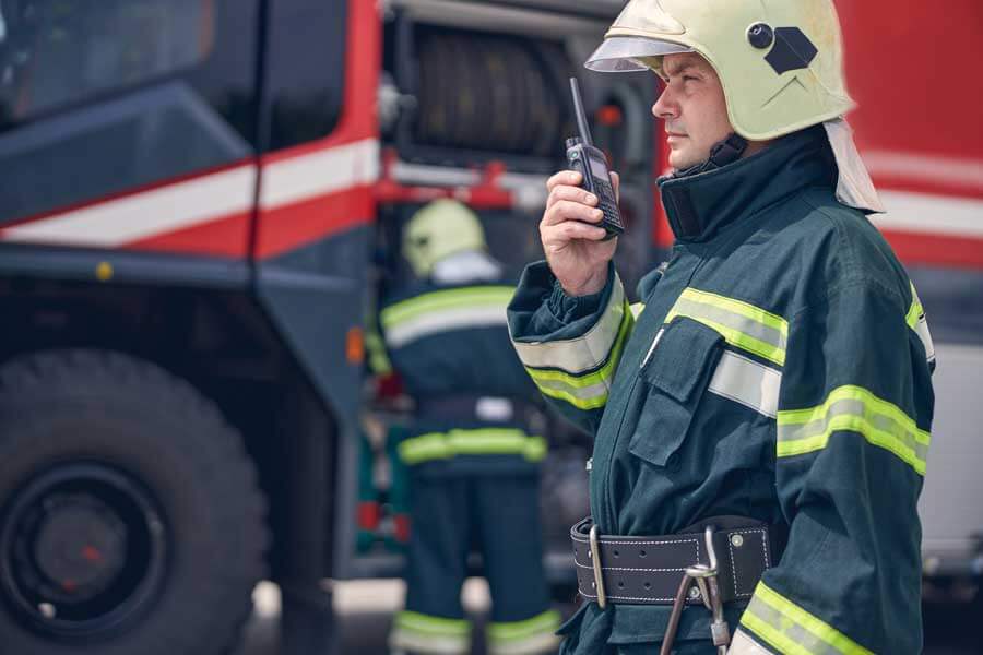 Un bombero usa un walkie talkie junto al camión de bomberos